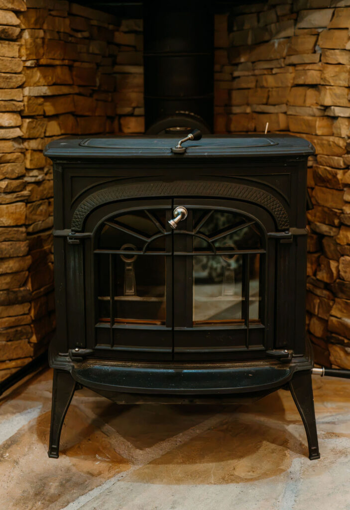 Rustic wood-burning stove set against a natural stone wall inside the Gatlinburg couples cabin.