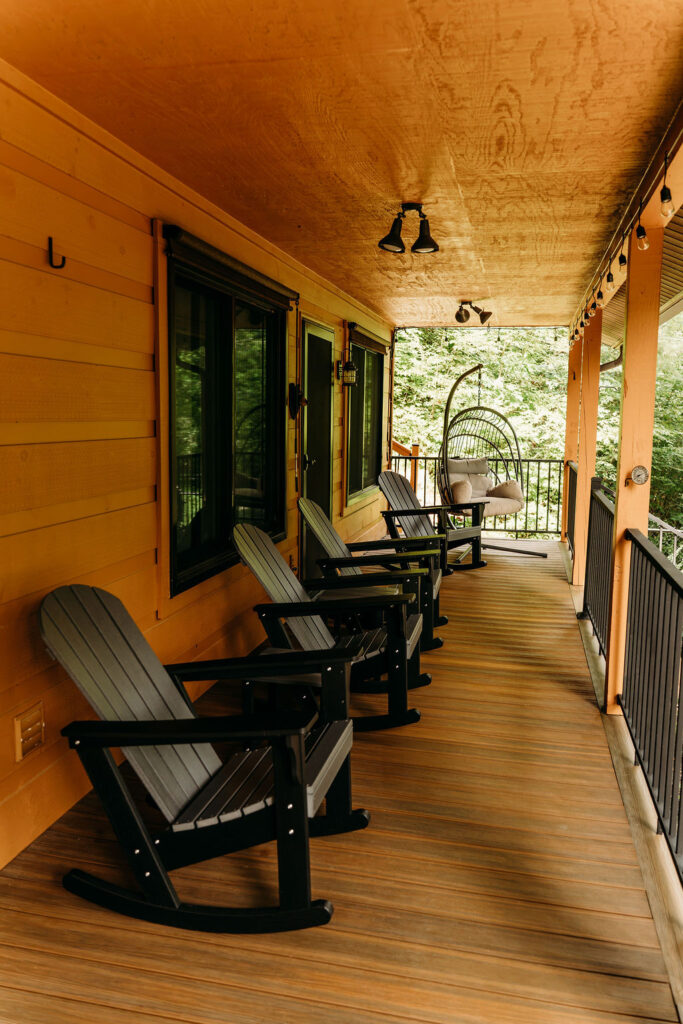 Covered wooden porch with rocking chairs overlooking the peaceful wooded surroundings at After the Trail.