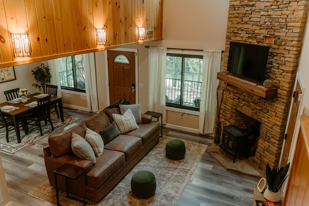 Cozy living room with vaulted wood ceilings, comfortable seating, and stone fireplace at After the Trail cabin in Gatlinburg.