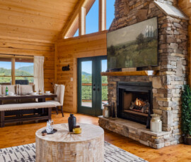 Open living room with stone fireplace and large windows at Bear Ridge Escape