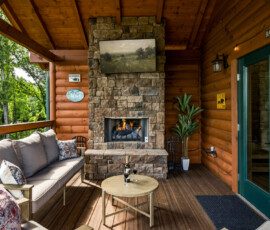 Stone fireplace and seating on the covered deck at Bear Ridge Escape