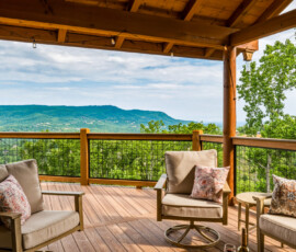 Covered outdoor seating area with stone fireplace and mountain views