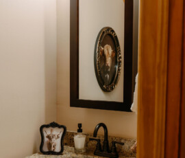 Rustic bathroom vanity with framed mirror and decorative accents inside the Gatlinburg cabin.
