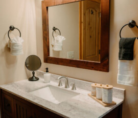 Bathroom vanity with sink, wooden framed mirror, and rustic accents at After the Trail.