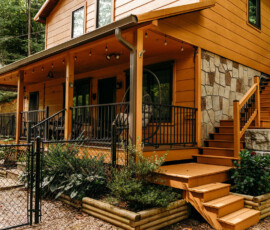 Covered front porch, wooden steps, and rustic cabin exterior surrounded by trees in Gatlinburg.