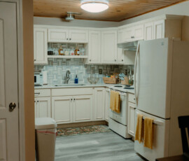 Fully equipped white kitchen with refrigerator, stove, and cabinets at After the Trail cabin.