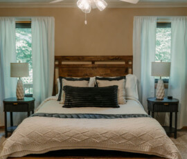 Queen bed with neutral bedding and bedside lamps in the Gatlinburg cabin bedroom.