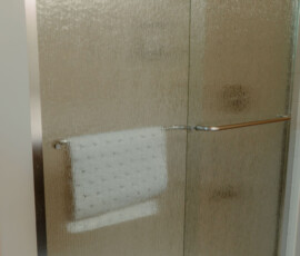 Glass shower enclosure with sliding doors and towel inside the Gatlinburg cabin bathroom.